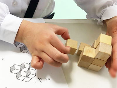 ピグマリオンの学具「ウッディブロック」を使ってプリントに記載された問題を実際に解いている