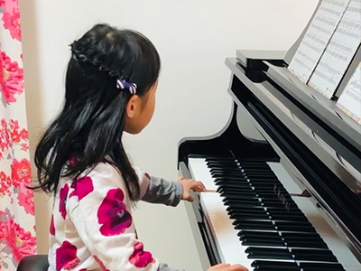楽譜を見てピアノを演奏している小さな女の子